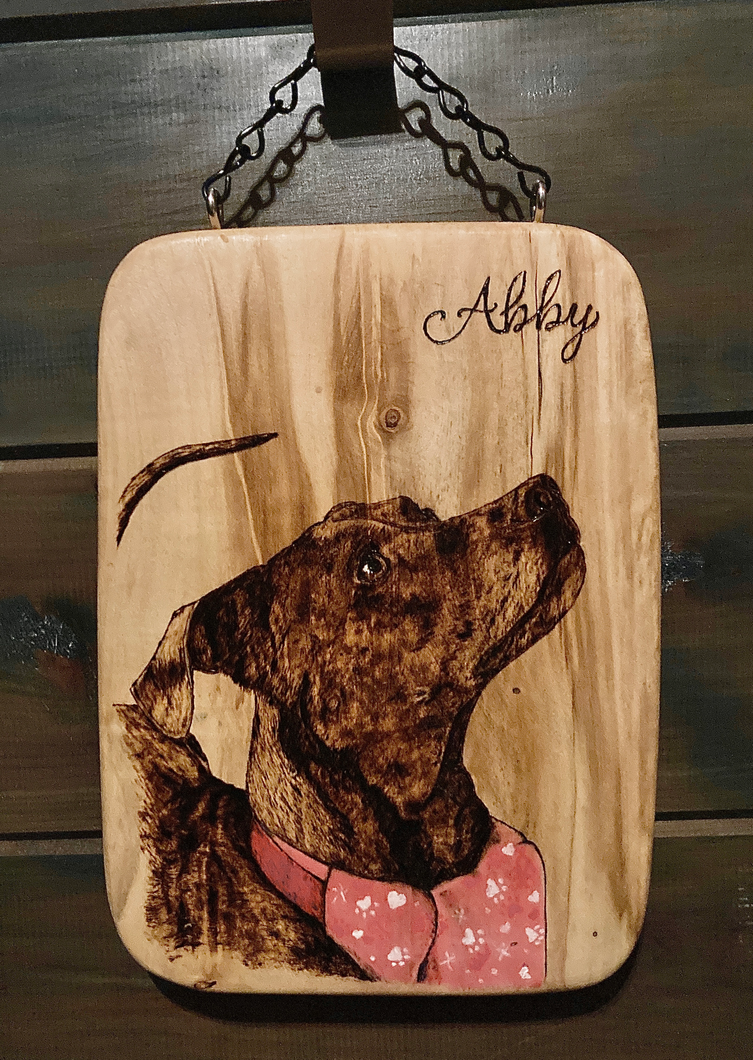Image of a dog named Abby burned on a piece of wood.