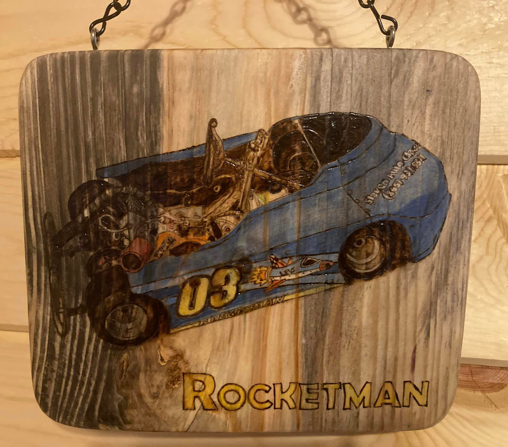 A go-cart wood burned and painted on a piece of wood.